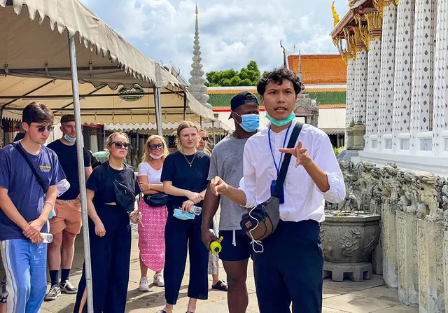 Arthur speaking to a group beside ornate temple architecture
