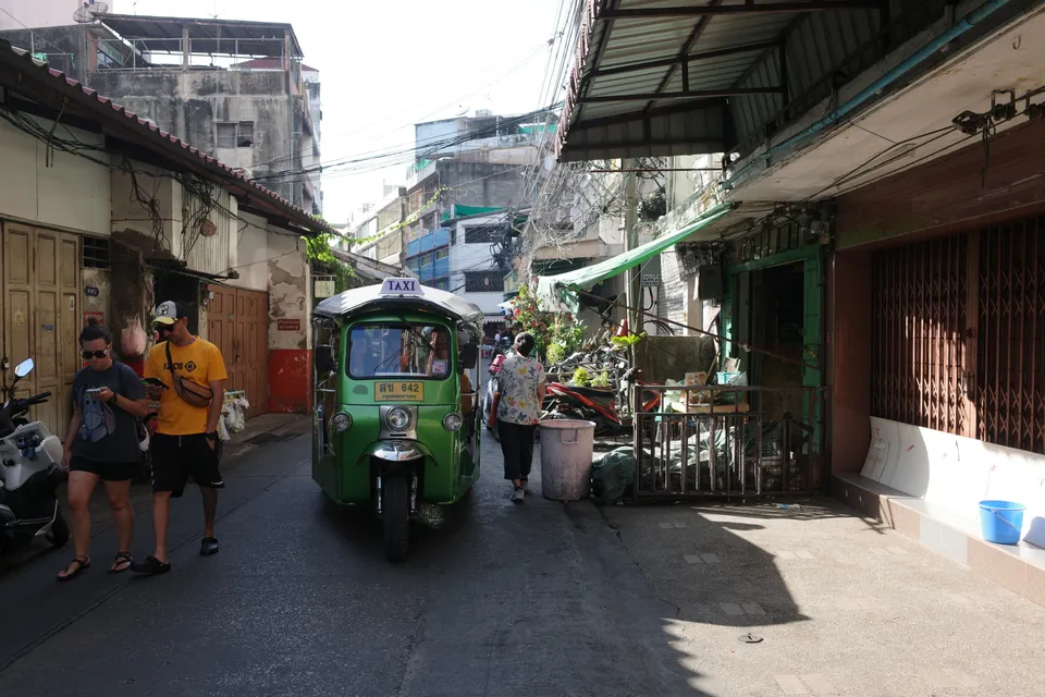 People and a green tuk-tuk on a lane in Talat Noi, Bangkok