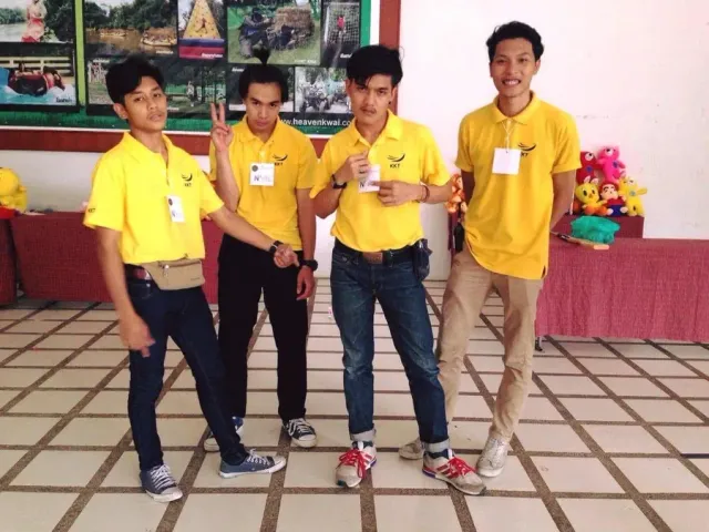 Four friends standing indoors in matching yellow shirts