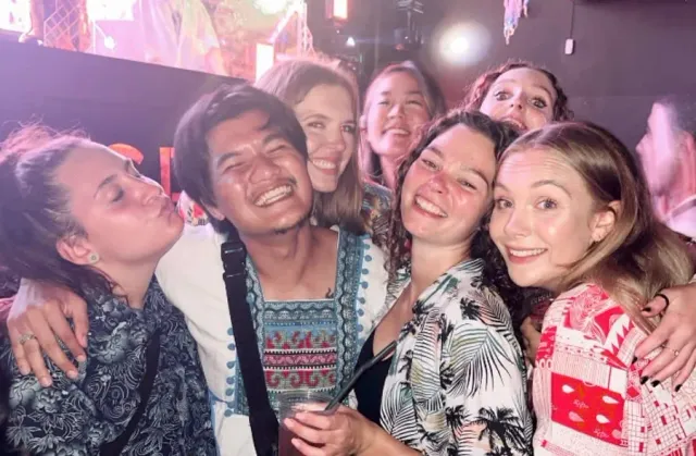 A smiling group gathering close for an evening selfie